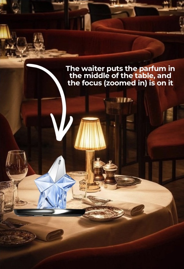 Storyboard frame — the waiter places the parfum at the centre of the table